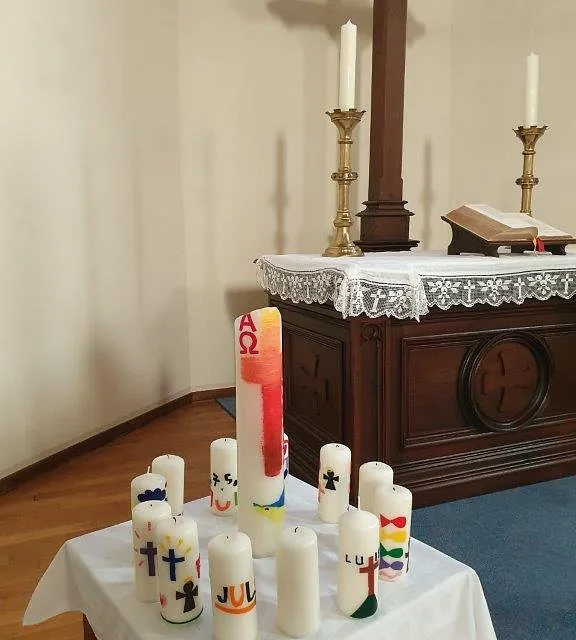 Dekorierte Kerzen, die vor einem Kirchenaltar aufgestellt sind.