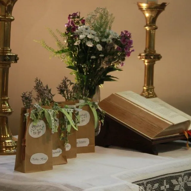 Kirchenaltar, dekoriert mit einem Buch, Blumen und kleinen Geschenktüten aus Papier.