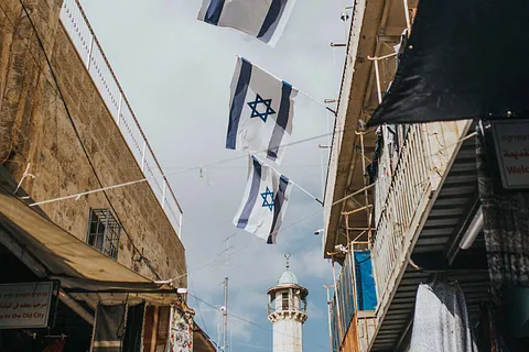 Israelische Flaggen zwischen Gebäuden mit einem Minarett.