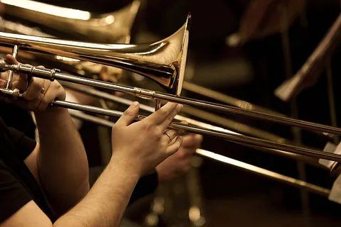 Hände eines Musikers beim Spielen einer Messingposaune.
