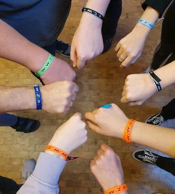 Menschen mit Armbändern führen Fäuste zusammen.
