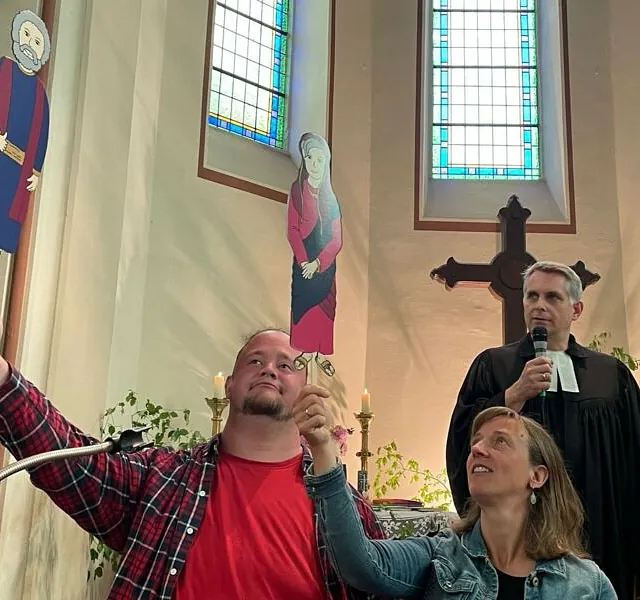 Menschen halten Pappfiguren in einer Kirche hoch.
