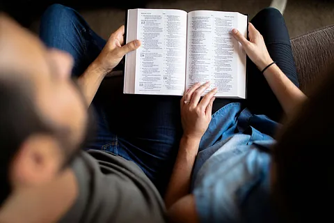 Draufsicht auf eine Person, die ein geöffnetes Buch hält.