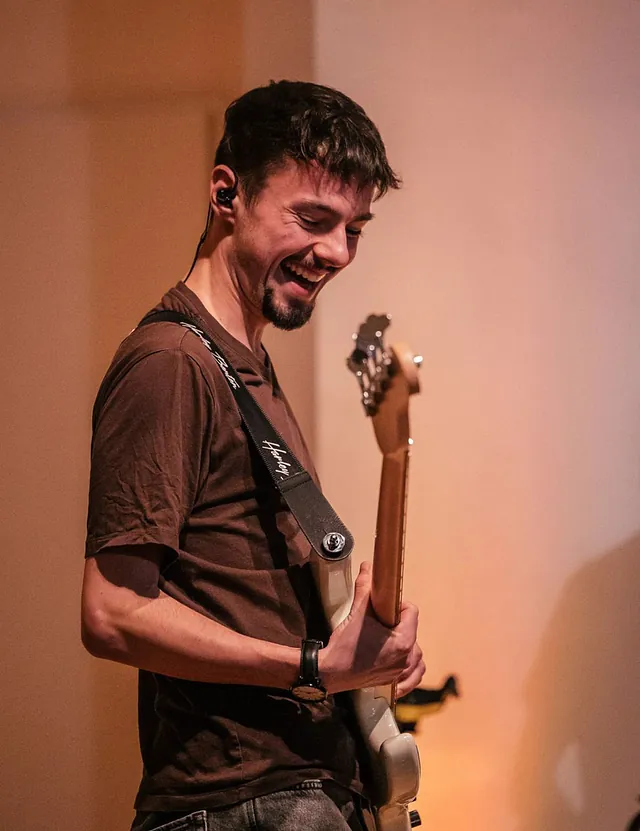 Lächelnder Mann, der eine E-Gitarre hält.